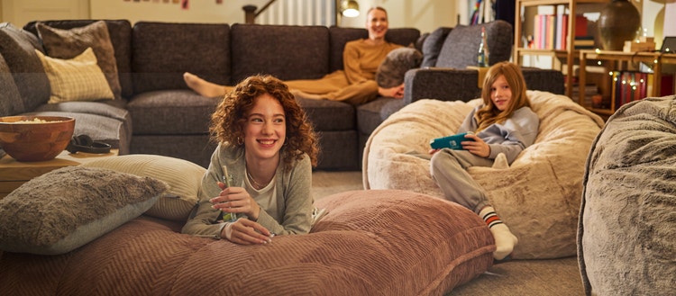 Two girls playing video games on Lovesac bean bag chairs.