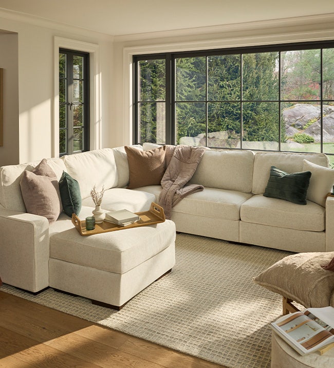 Woman using a brown, Lovesac, sectional couch with a storage seat.