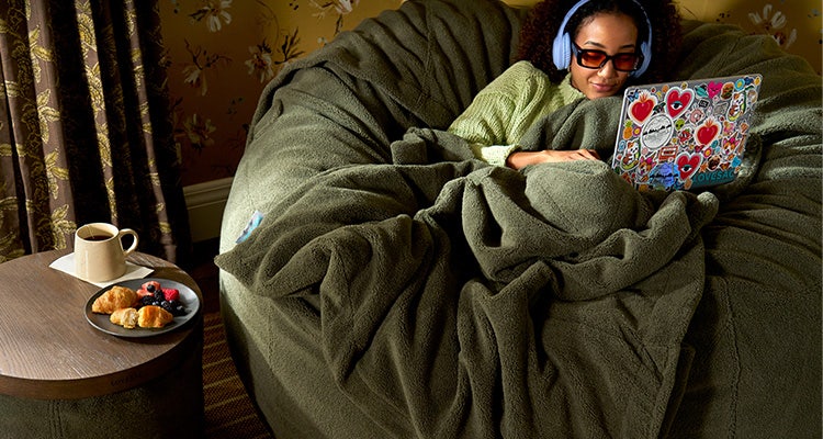 Woman relaxing in a green bean bag chair and blanket