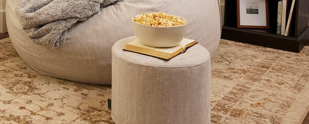 A squattoman with a book and bowl of popcorn on top of it