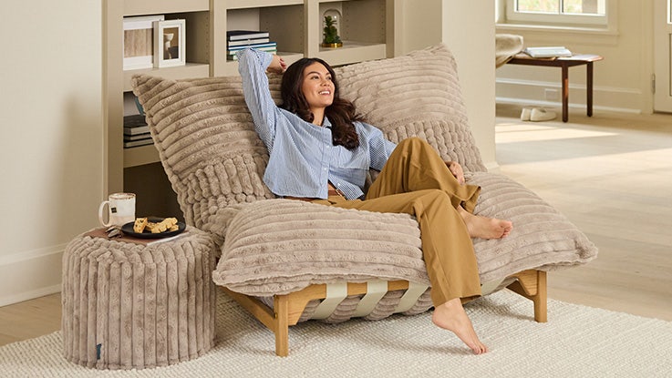A woman sitting in a Lovesac PillowSac Accent Chair in her living room.