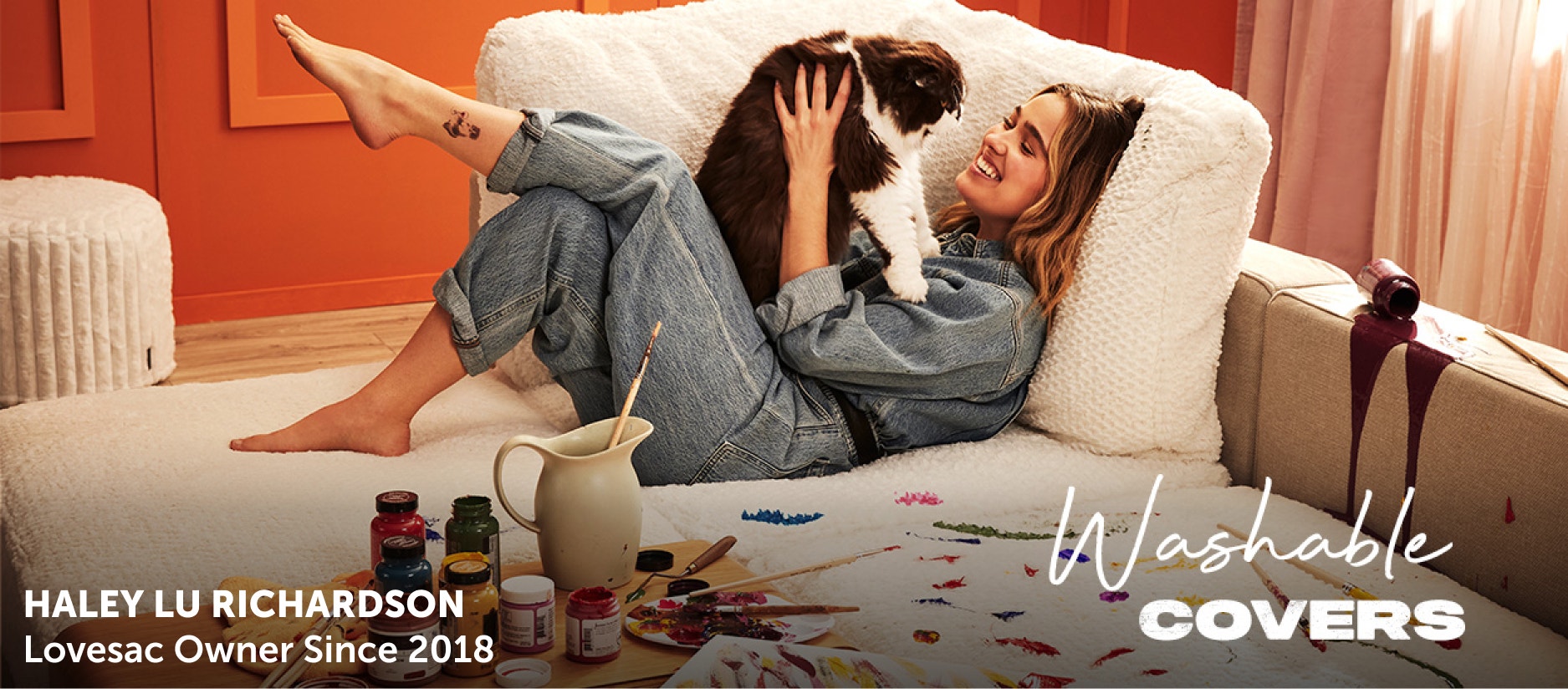 Celebrity actress Haley Lu Richardson and her cat lounge on cream-colored Lovesac Sactionals. Lovesac has been rewriting the rules of comfort for 25 years, and offers washable covers.