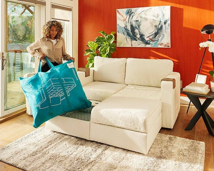 Woman ready to use her Lovesac Guest Rest Bedding Kit on her adaptable couch.