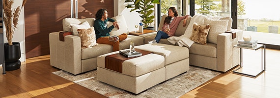 A young couple rests on their white/beige Lovesac Sactionals setup.