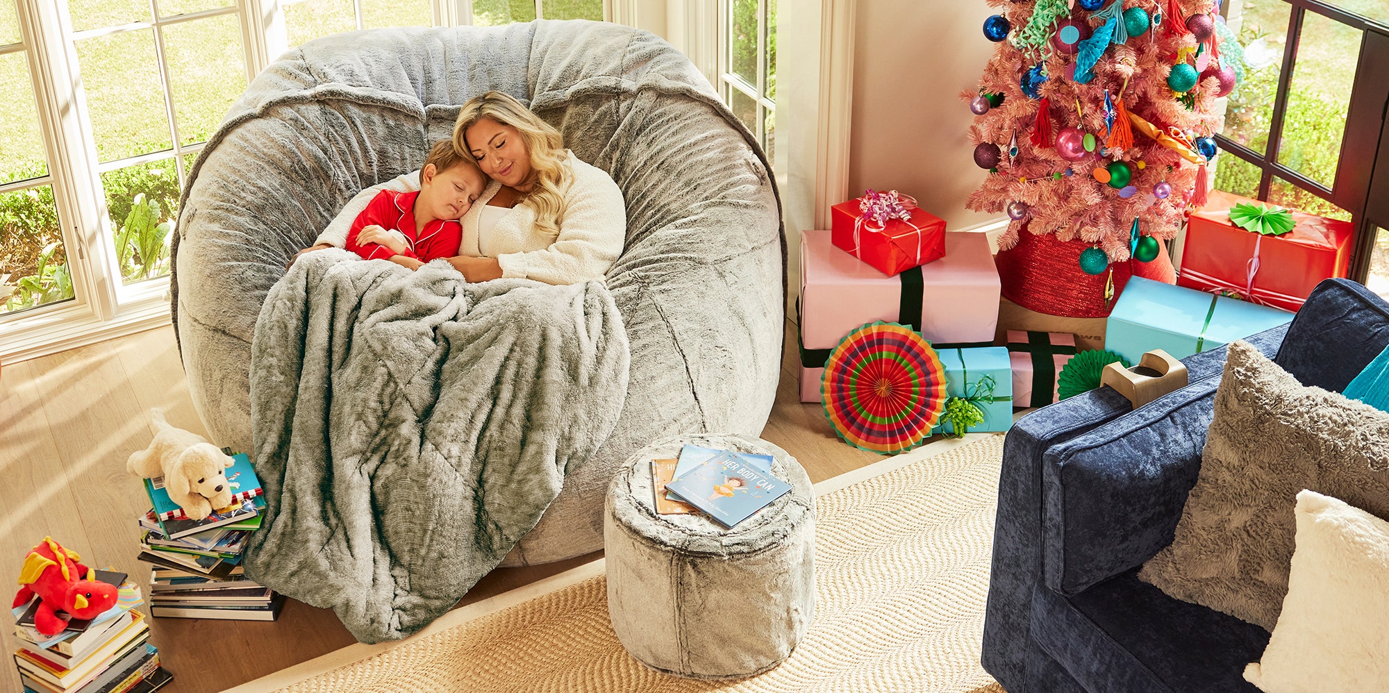 Woman and child relaxing on Lovesac Sac large bean bag chair with a blanket and Squattoman footstool in living room
