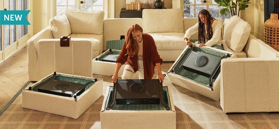 Woman Placing StealthTech Satellite Subwoofers Into Lovesac Sactionals Seats.