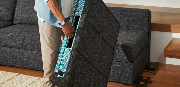 Person rearranging couch with Satellite Side StealthTech system component