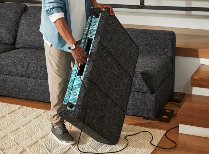 Person rearranging couch with Satellite Side StealthTech system component