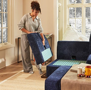 Woman Rearranging Lovesac Sactionals Seats and Sides