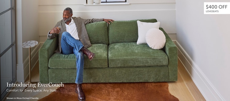 Man sitting on a green, Lovesac EverCouch loveseat in a living space
