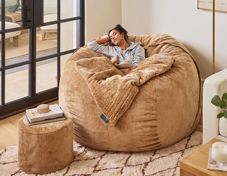 Woman relaxing on a caramel colored Lovesac beanbag chair