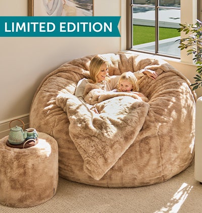 Woman relaxing in her Lovesac Pillowsac Accent Chair in green fabric