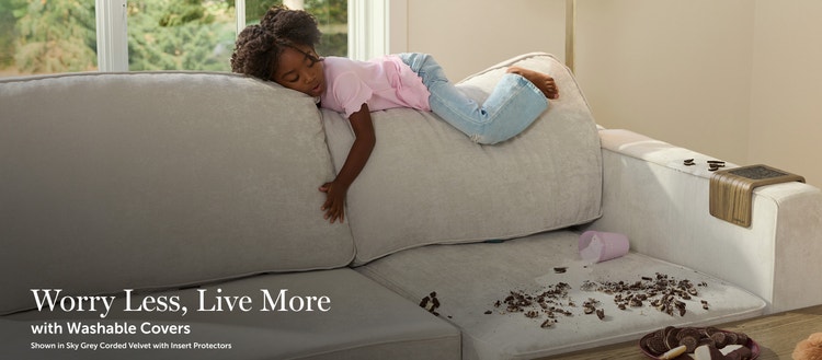 Child sleeping on a Lovesac sectional couch with a mess