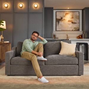 Man relaxing on a grey loveseat in a living space