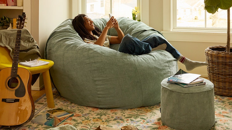 Woman relaxing on her brown Lovesac beanbag chair
