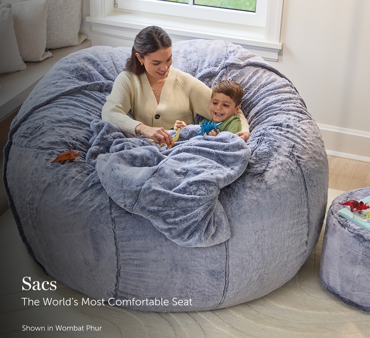 Mother and child relaxing in a large, grey, Lovesac beanbag chair in a living room