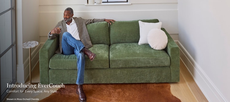 Man sitting on a green, Lovesac EverCouch loveseat in a living space