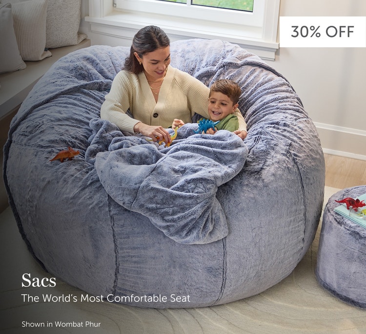 Mother and child relaxing in a large, grey, Lovesac beanbag chair in a living room