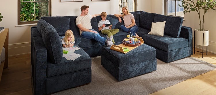 Family relaxing on a green Lovesac sectional couch