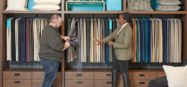 Two people looking at Lovesac fabric samples for sectional couches in a showroom.