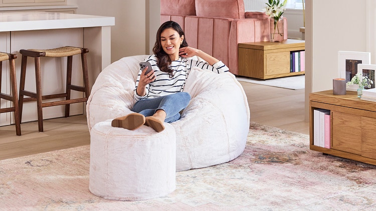 Woman relaxing on her peach colored Lovesac beanbag chair