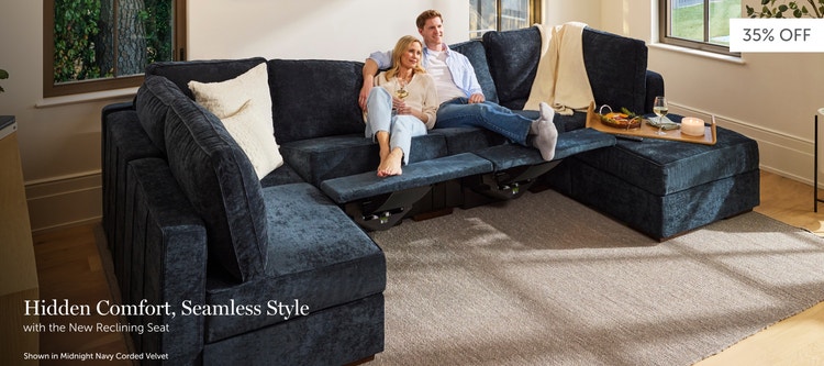 Couple relaxing on a dark blue, Lovesac sectional couch with recliners