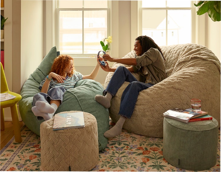 Woman relaxing on a grey colored Lovesac bean bag chair with her dog.