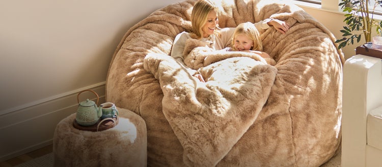 Mom and daughter lounging in a caramel-colored Lovesac beanbag chair set