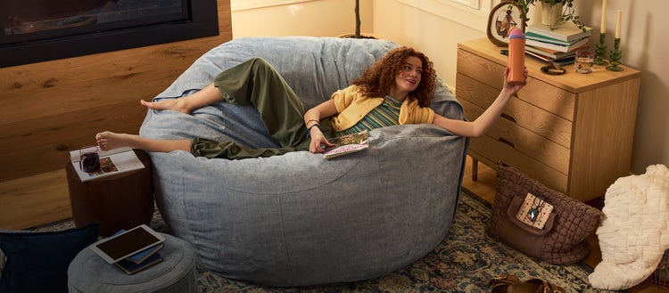 Man and dog lounging in a brown-colored Lovesac beanbag chair set