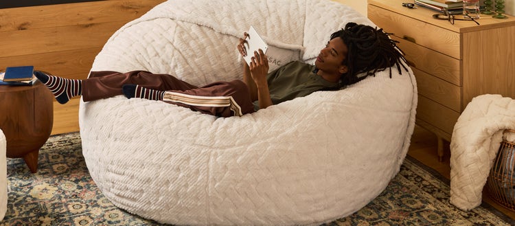 Man and dog lounging in a brown-colored Lovesac beanbag chair set